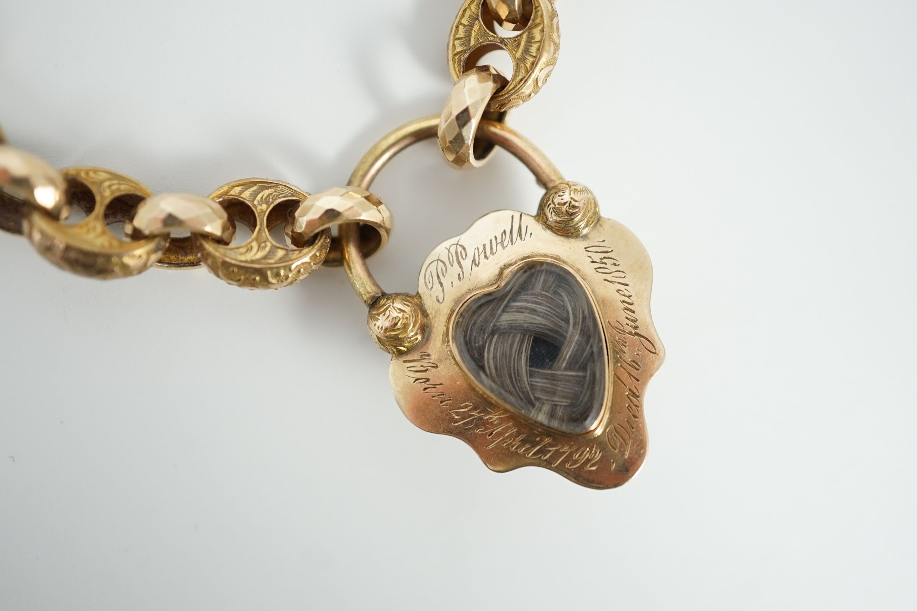 A Victorian engraved and facetted link gold mourning bracelet, with pear shaped foil backed? garnet set heart shape padlock